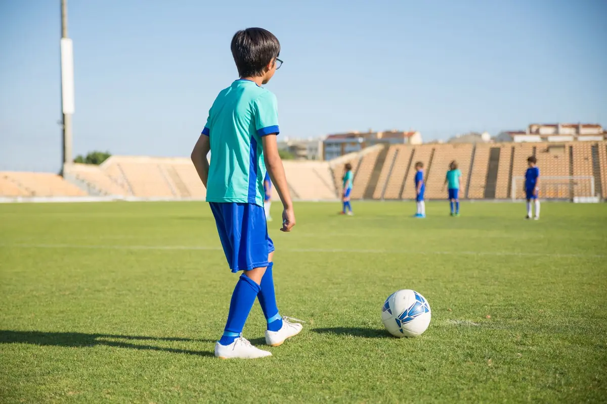 A player with the ball at his feet, looking up at teammates spread across the field